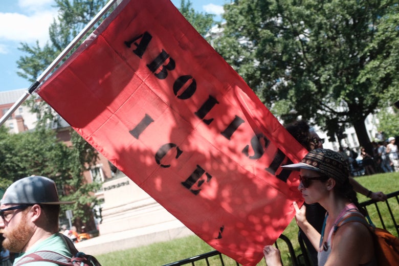 Two activists carry an “Abolish ICE” banner through Lafayette Park.